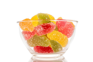 Several sweet marmalade candies in a glass plate, macro, isolated on white background.