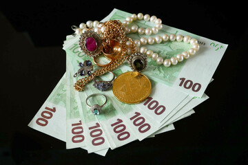 golden jewellery and stack of euro money on black background, pawnshop
