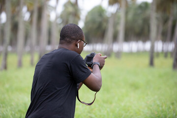 A young photographer takes pictures with a DSLR camera in an agricultural field in Africa....