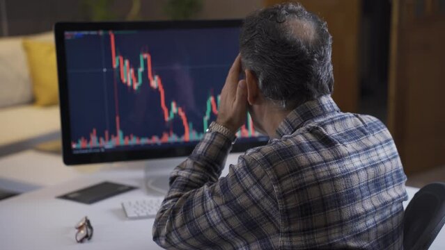 Stressed trader at home watching stock market on laptop and getting upset seeing falling chart candles.
Unconscious investor buys and loses Loss stocks. Bitcoin and stock market trading concept.
