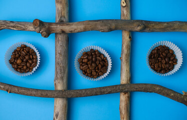 fragrant coffee beans are poured in a cupcake mold on a bright blue background, surrounded by...