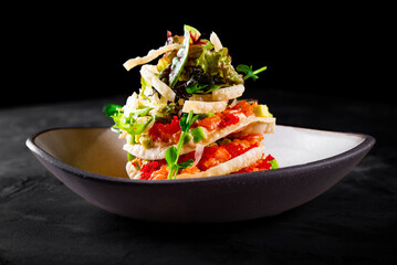 Millefeuille with salmon and avocado on dark background
