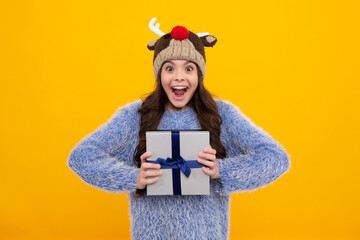 Funny kid girl in winter wear holding gift boxes celebrating happy New Year or Christmas. Winter holiday. Amazed teenager. Excited teen girl.