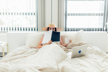 digital nomad and remote working concept - young lady in luxury hotel room bed with hat coffee and laptop - obrazy, fototapety, plakaty