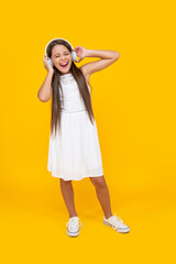 sing teen girl listen music in headphones on yellow background