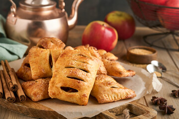 Hand pies. Mini puff pastry or hand pies stuffed with apple and sprinkle sugar powder in wooden plate. Homemade pie snack with crust for breakfast rustic photo.  Copy space.