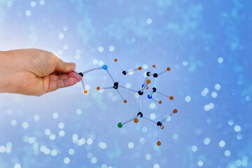close-up of female scientist's hands holding of molecules and atoms in compound on light...