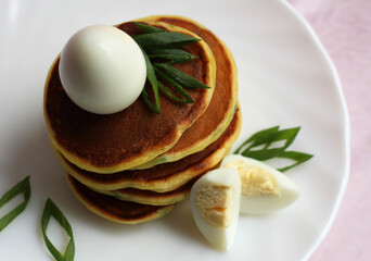 mini pancakes with quail egg and green onions on a white plate