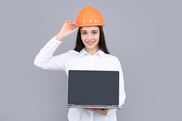 Business builder woman with laptop computer, portrait on gray. Portrait of female worker in hardhat helmet.