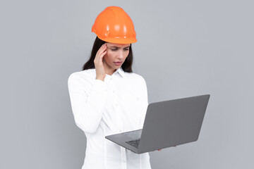 Business builder woman with laptop computer, portrait on gray. Portrait of female worker in hardhat helmet.
