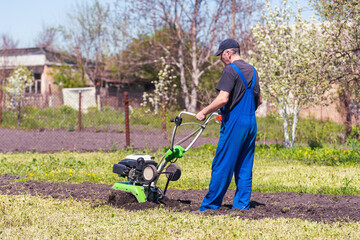 Farmer man plows the land with a cultivator preparing the soil for sowing