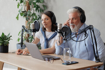 female and male podcasters record audio content in sound studio. social media, news program on...