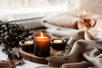 warm cozy window arrangement, winter or autumn concept, candles throw lights - Powered by Adobe