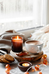 warm cozy window arrangement, winter or autumn concept, coffe, candles throw lights