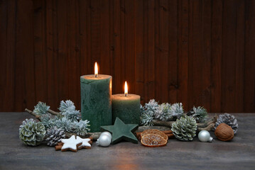 Rustikale Dekoration mit grünen Kerzen und Weihnachtsschmuck vor einem schäbigen Holzhintergrund...