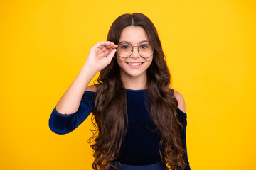 Happy face, positive and smiling emotions of teenager girl. Teenager child wearing glasses on yellow studio background. Cute girl in eyeglasses.