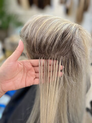A girl in a beauty salon does hair extensions. Keratin hair extension. Cold hair extensions. soft...