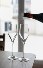 Pouring champagne or rose wine to two glasses. Festive drinks to celebrate holiday season at party. 