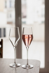 Pouring champagne or rose wine to two glasses. Festive drinks to celebrate holiday season at party. 