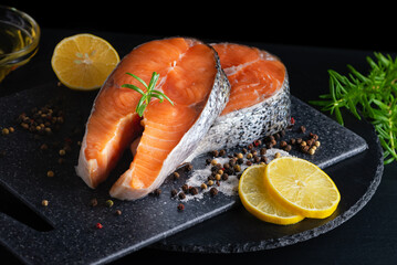 Delicious fresh salmon with lemon, salt and spices on a black table. Concept of healthy seafood