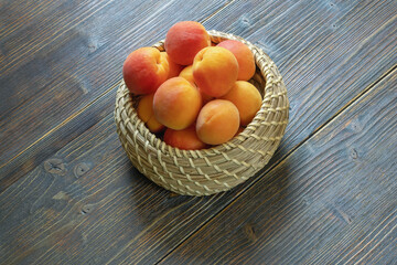 Ripe apricots in small basket on dark rustic table. Copy space