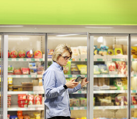  Man choosing frozen food from a supermarket freezer., reading product information