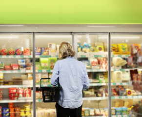  Man choosing frozen food from a supermarket freezer., reading product information