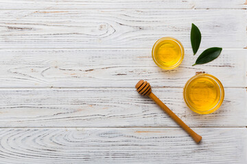 Honey jar with wooden honey dipper on white background top view with copy space. Delicious honey bottle