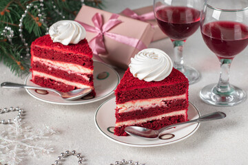 Two servings of Red Velvet cake, wine and gifts on gray background, dessert for the New Year