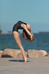 young graceful and flexible gymnast in swimsuit by the sea