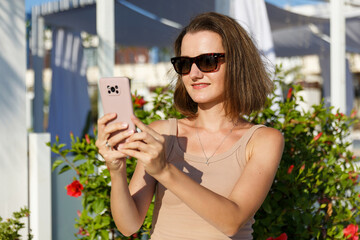 A young stylish woman communicates on a smartphone on a city street