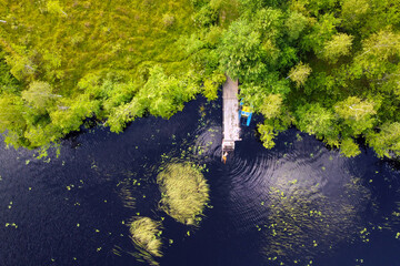 Aerial view of lake with wooden pier. Mole on summer lake for fishing. Aerial landscape, green...