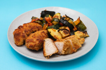 Delicious crispy fried breaded chicken breast strips with baked vegetables