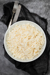 Boiled rice in a bowl on gray background.