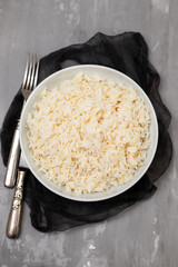 Boiled rice in a bowl on gray background.