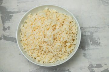 Boiled rice in a bowl on gray background.