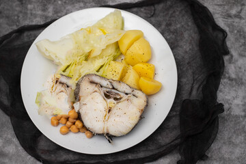 baked vegetables with boiled fish on white plate