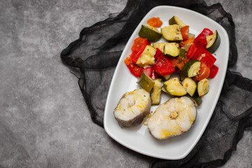 baked vegetables with boiled fish on white plate