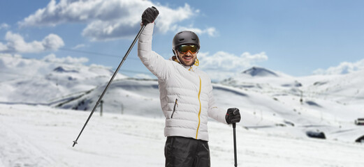 Man with skis lifting a skiing pole on a mountain