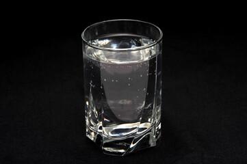 Drinking water in a glass on a black background