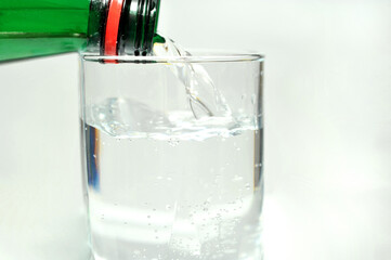 Bottled mineral water and a glass on a white background