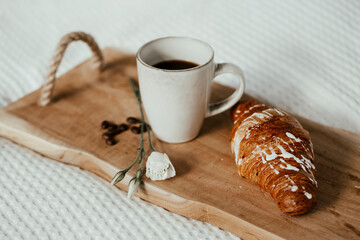 Cup of coffee and croissant with white flower - morning surprise in bed 