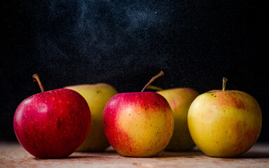 a bunch of apples on the table beautiful red-pink green apples on a dark black background