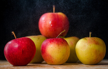 a bunch of apples on the table beautiful red-pink green apples on a dark black background
