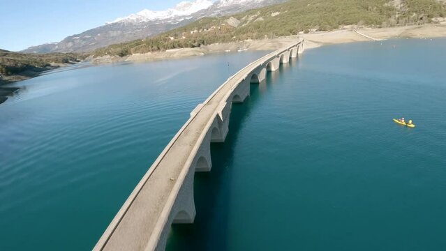 Fly over an old stone bridge over Lake Savines in the Hautes-Alpes