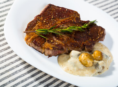Image of beef entrecote with mushroom sauce on the plate indoors.