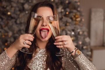 A girl in a shiny silver dress celebrates the New Year. Cheerful holiday mood.