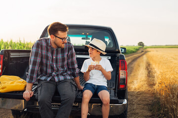 Boy is having a snack with his father in the field