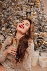 A girl in a shiny silver dress celebrates the New Year. Cheerful holiday mood.