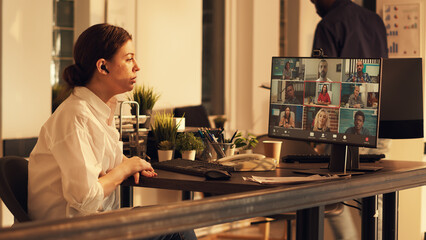 Startup employee talking to colleagues on online teleconference, attending remote company meeting with webcam on computer. Using videocall telecommunications in corporate office.